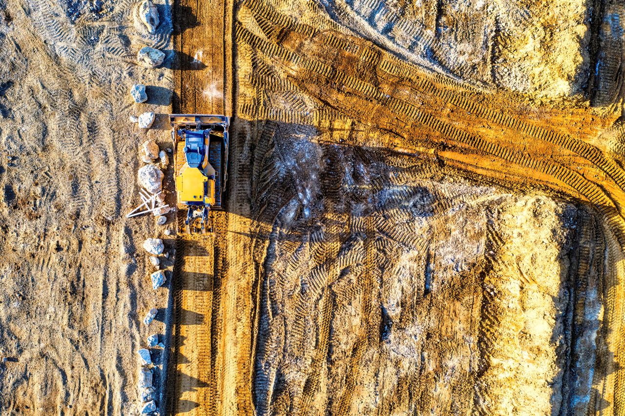 Top-down view of a bulldozer moving sand and rocks at a construction site in Rochester, MN.